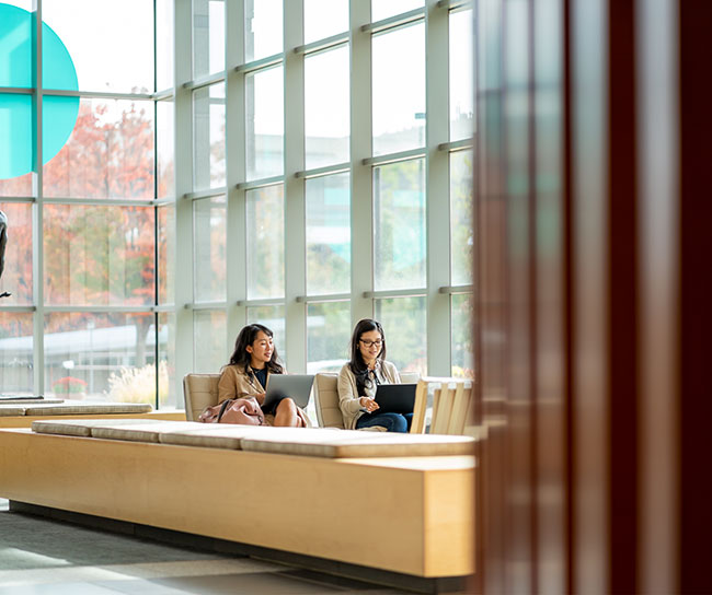 Two employees in the lobby on their laptops