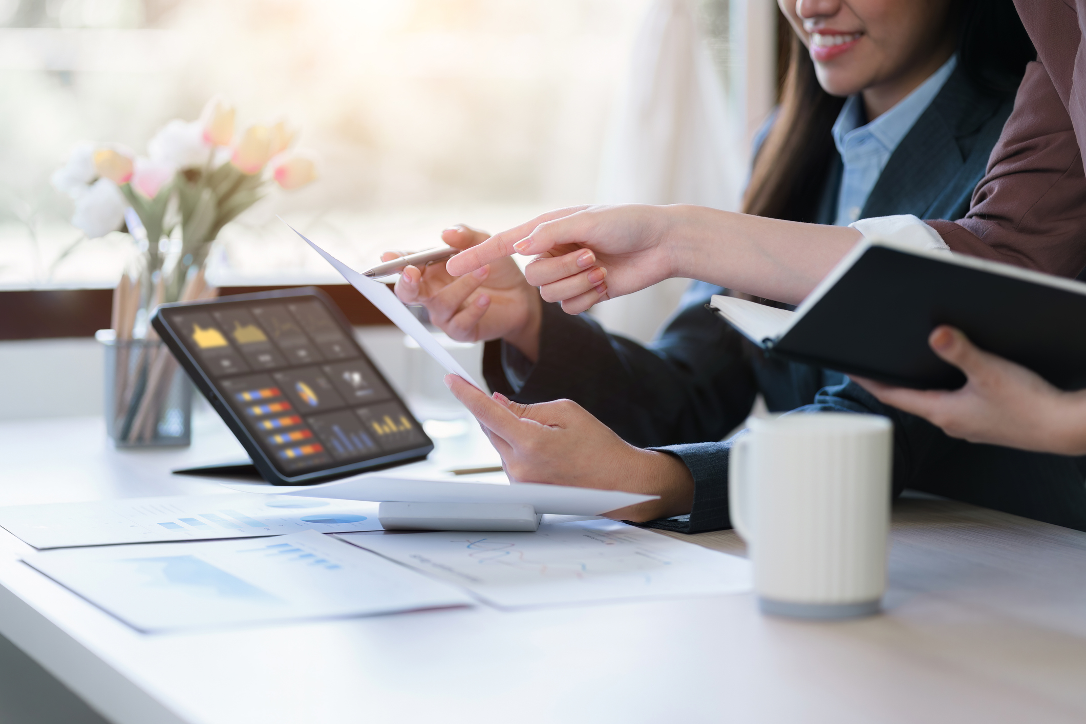 hands of women in suits using data dashboard