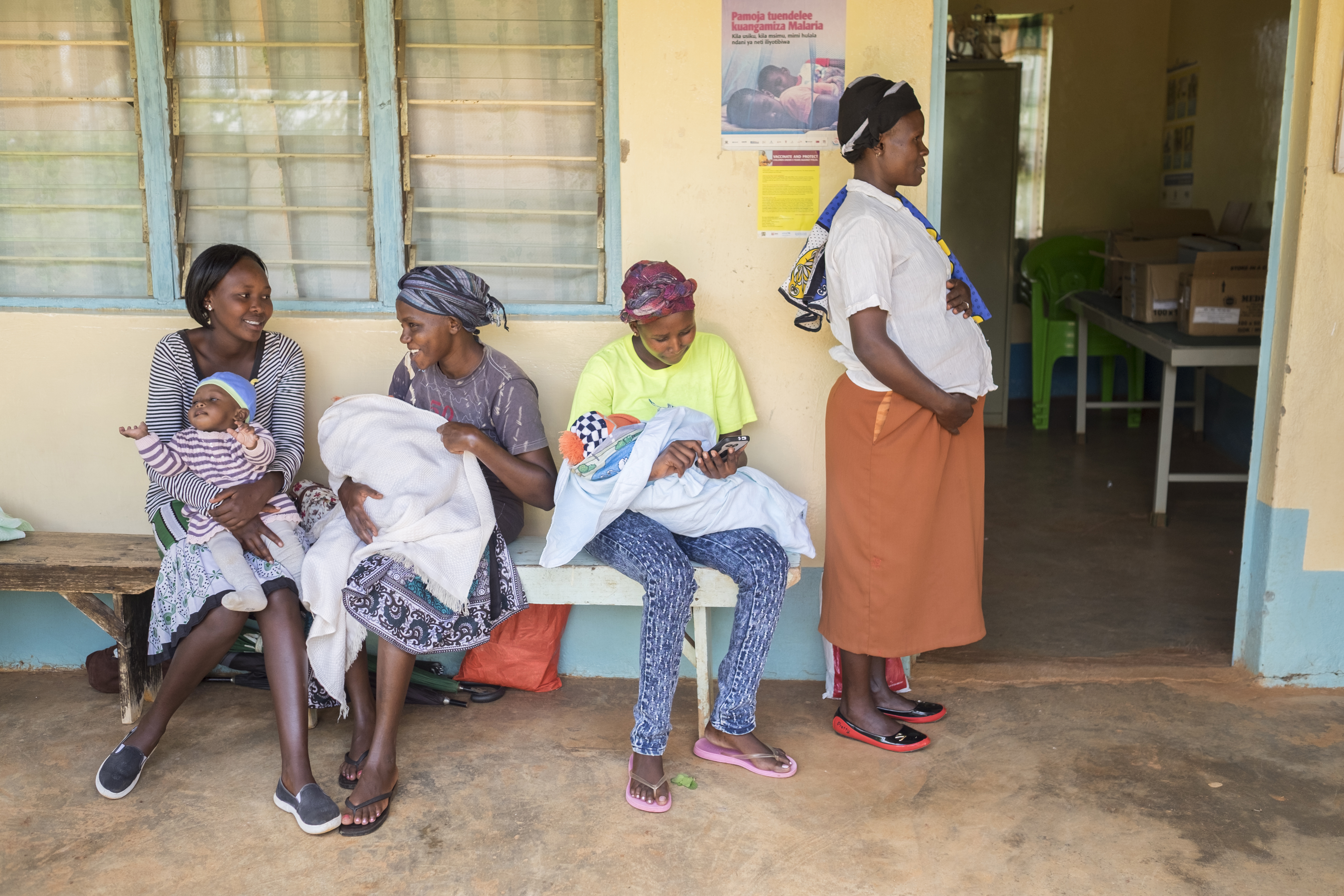 Women sitting on bench, holding babies