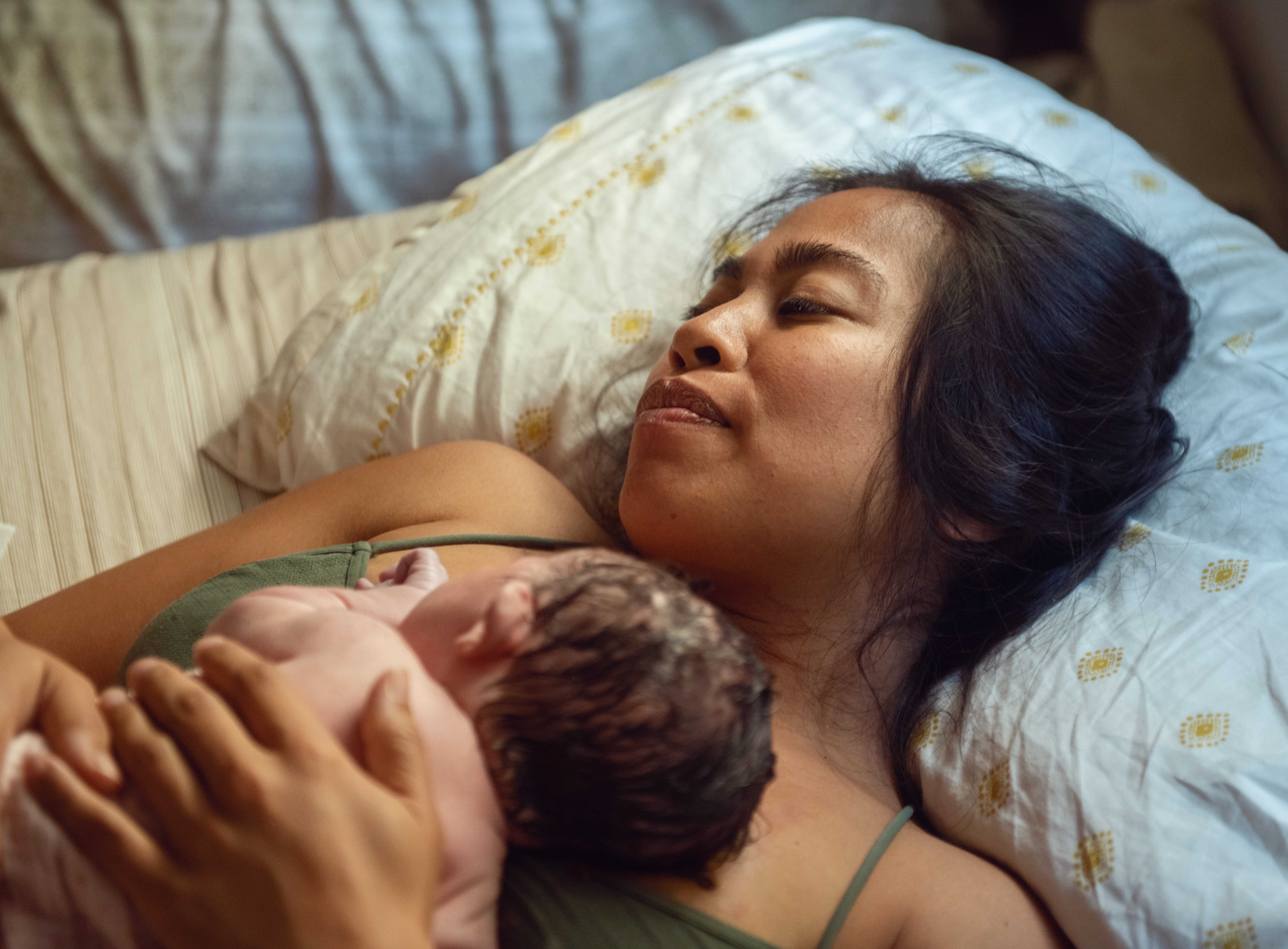 mother laying down in bed with her newborn